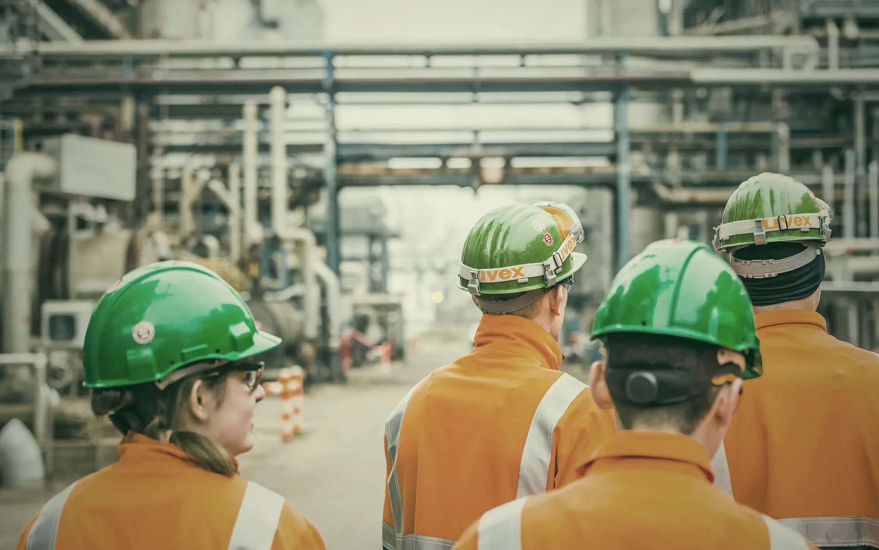 Refinery employees in hard hats walking through the plant